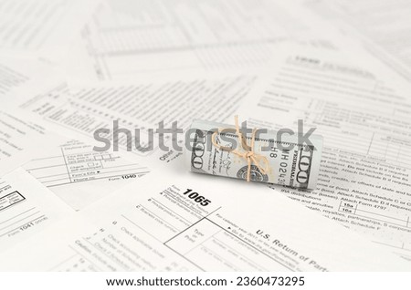1065 U.S. Return of Parentship Income form with roll of american dollar banknotes close up. Concept of tax period in United States Royalty-Free Stock Photo #2360473295