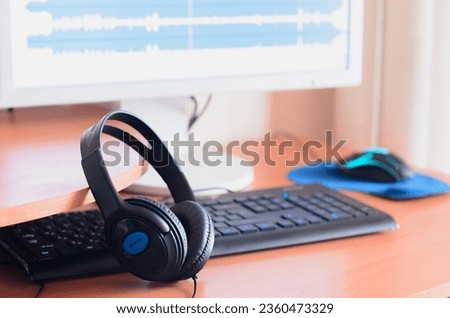 Big black headphones lie on the wooden desktop of the sound designer. Workplace for music creator. Selective focus