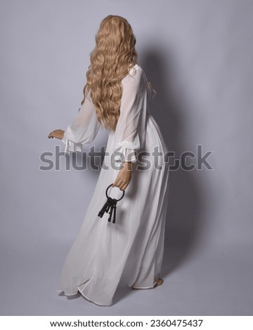 Full length portrait of blonde woman  wearing  white historical bridal gown fantasy costume dress. Standing pose, facing backwards walking away from camera, isolated on studio background.