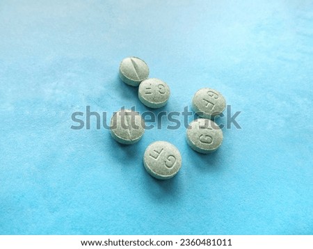 Medication for treating inflammation, treating allergies and swelling, green pills isolated on a turquoise background
