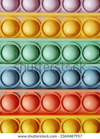 Close-up of a Pop-it toy with a rainbow background.