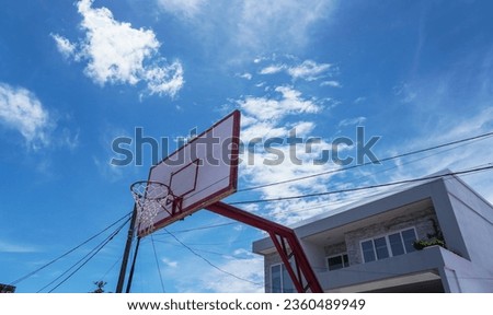 In front of the house, a basketball hoop stands tall, against a backdrop of clear blue skies.