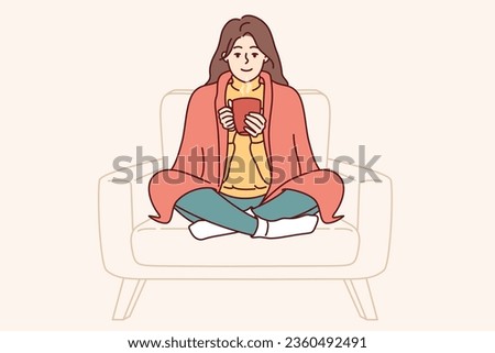 Woman with blanket on shoulders drinks hot tea to cheer up and feel comfortable in warm and cozy atmosphere. Girl smiles sweetly and drinks hot coffee to gain strength before going to college Royalty-Free Stock Photo #2360492491