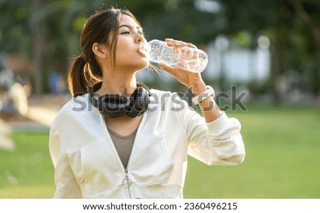 Portrait sport asian beauty body slim woman drinking water from a bottle while relax and feeling fresh,  refresh drink,  wellness, healthcare, mineral at green park.Healthy liquid lifestyle concept Royalty-Free Stock Photo #2360496215