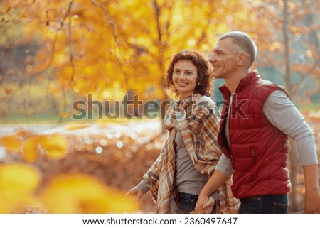 Hello autumn. smiling modern couple in the park walking. Royalty-Free Stock Photo #2360497647