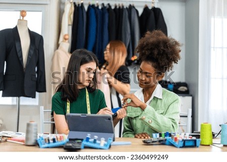 Portrait of young african american woman and young girl fashion designer stylish sitting and working with color samples.Attractive two designer girl work with colorful fabrics at fashion studio