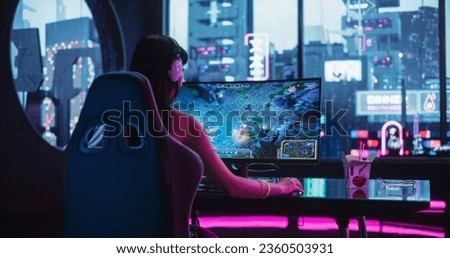 Young Woman Wearing Futuristic White Clothes and Neon Rings, Playing Online Strategy Video Game on a Computer with Curved Monitor. Beautiful Girl in Headphones Participating in an eSports Match Royalty-Free Stock Photo #2360503931
