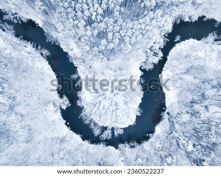 Top down view of frozen forest and cold river in winter. The trees are covered with snow. Royalty-Free Stock Photo #2360522237