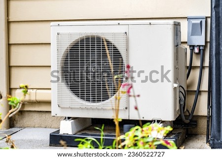 In an outdoor setting, a newly installed mini-split system sits in the sun. This is a high efficient mini split heat pump installed by an HVAC professional.  Royalty-Free Stock Photo #2360522727