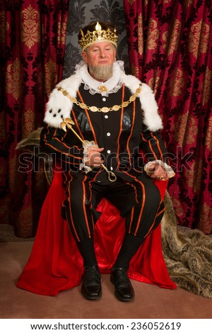 King in tudor costume sitting on his throne holding his scepter Royalty-Free Stock Photo #236052619