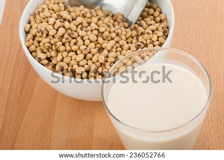 Soy milk in glass with soybeans and  transfer scoop in bowl  on wood table