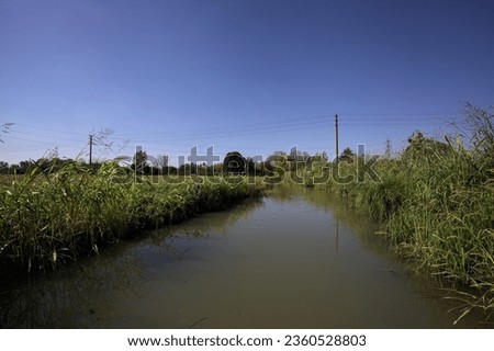 Trench  full of water between mowed fields on a sunny day in the italian countryside