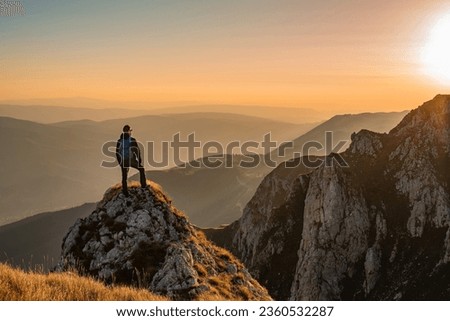 A man who hikers enjoys a break look at the top of the mountain at sunset adventure travel. Royalty-Free Stock Photo #2360532287