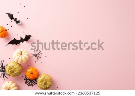 Vogue Halloween treats setup. Top view shot of themed pieces: tiny glittering pumpkins, eerie spiders, spiderweb, bats, and confetti on soft pink surface. Great for messages or marketing