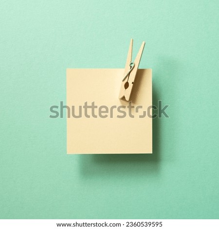 Brown kraft memo paper, sticky note pad with wooden clip on green background. top view, copy space