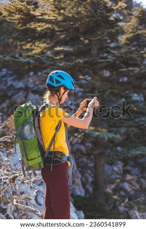 climber on top of the mountain takes a photo. Woman traveler takes a photo on a modern smartphone, makes beautiful pictures of beautiful mountain landscapes. mountain climbing and adventure.