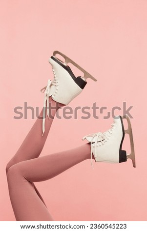 Winter mood. Slender female legs in pink tights, wearing white skates over pink background. Colorful photography. Concept of fashion, creativity, imagination. Copy space for ad