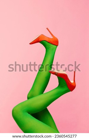 Matching colors. Slender female legs in green tights and orange heeled shoes over pink background. Colorful photography. Concept of fashion, creativity, imagination. Copy space for ad