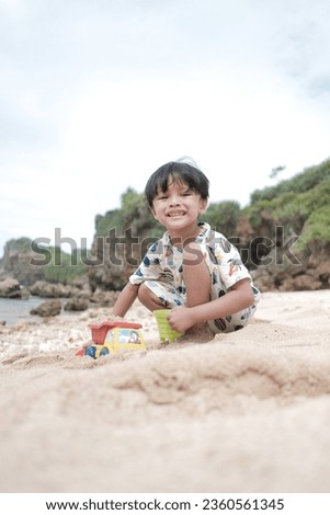 An Indonesian boy is playing cars on white sandy beaches. photos to describe the concept of childhood who likes to play in outdoor