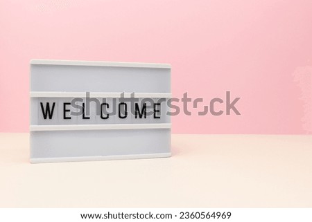 Word Welcome. Lightbox with letters in front of pink background. Place for text.