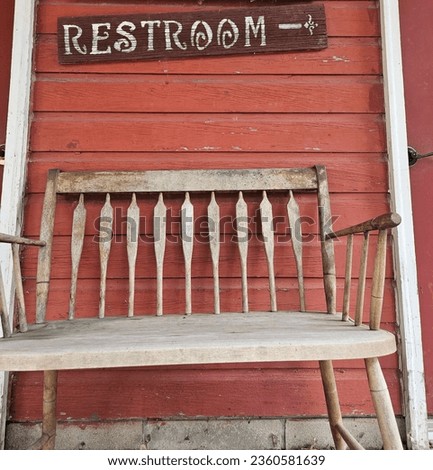 Old bench in front of restroom sign