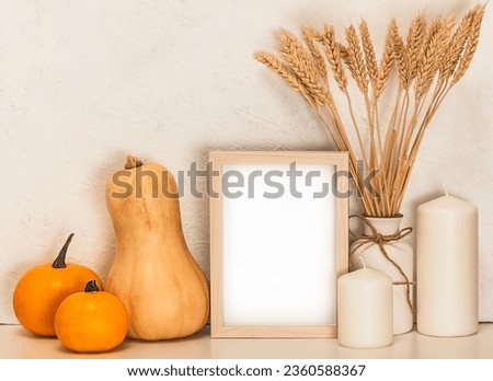 Autumn holidays concept.Thanksgiving.Autumn decor. Frame, candles, white vase with ears of wheat and pumpkins on a white table.