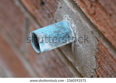 Corroded overflow pipe coming out of a brick wall