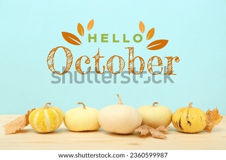 Pumpkins and autumn leaves on wooden table. Hello, October