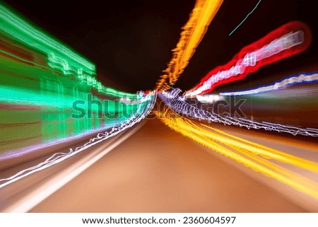 Moving lights in highway tunnel in Germany. Colorful traces of lamps, signs acaused by motion of fast car seen from drivers seat at night. Blurred abstract traffic background with longtime exposure. Royalty-Free Stock Photo #2360604597