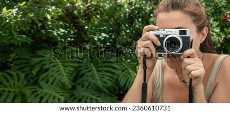 A woman taking pictures with a vintage camera outdoors. Traveling and photographing concept. Panorama banner with copy space