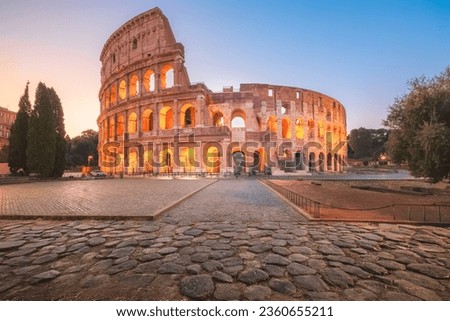 Iconic Flavian Amphitheatre, the ancient Roman Colosseum, a famous tourist landmark illuminated at twilight and dawn in historic Rome, Italy. Royalty-Free Stock Photo #2360655211