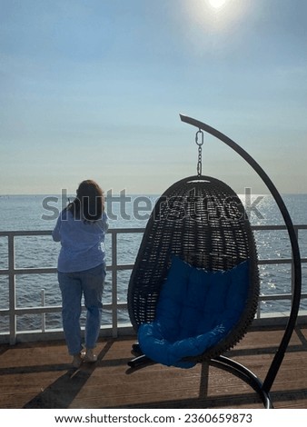 Woman standing near the seat and the sea 