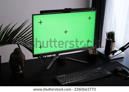 Green monitor screen in a tropical interior. Workspace for podcasting and video blogging. Chroma key for use as a mockup.