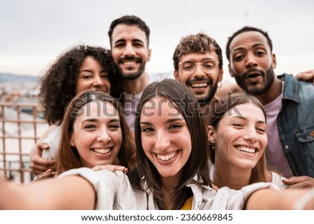 Diverse cheerful group of friends taking a selfie in a rooftop party.Multiracial young happy people smiling while taking a picture in a terrace.