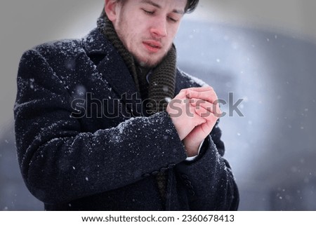 Portrait of frozen young man at winter cold snowy day, shivering  Royalty-Free Stock Photo #2360678413