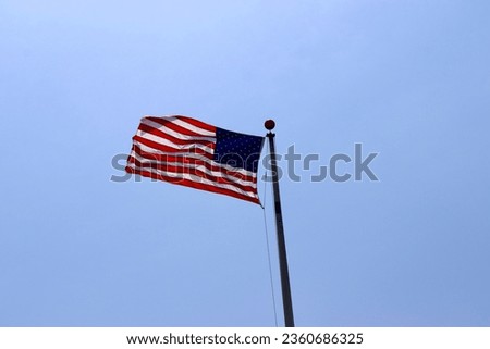 The US flag waving in the wind with the blue sky background.