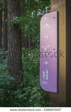 Information stand on forest trail. Destination sign in parkland. Parking sign and WC sign on information board. Recreation zone direction in park. Signage on national park path. Arrows on hiking trail