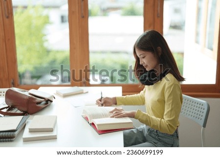 Education concept, Asian female read a book and writing notes, self learning.
