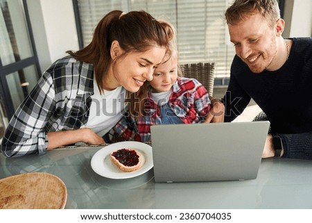 Happy family of three watching cartoon at laptop computer