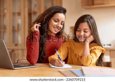 Homeschooling And E-Learning. Arabic Mom And Daughter Near Laptop Doing Kid's Homework Together, Mother Or Teacher Helping Preteen Schoolgirl With School Studies, Schooler Taking Notes Indoor