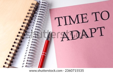 TIME TO ADAPT word on pink paper with office tools on white background