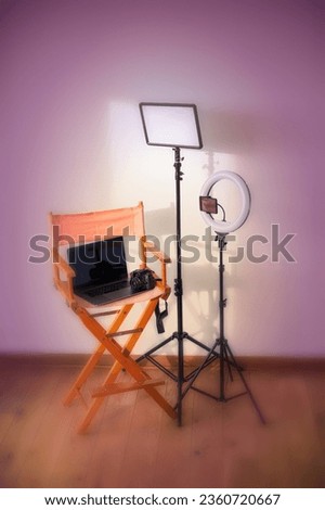 Director's chair, ring lights, digital camera with laptop and hats on colorful background with recording equipment