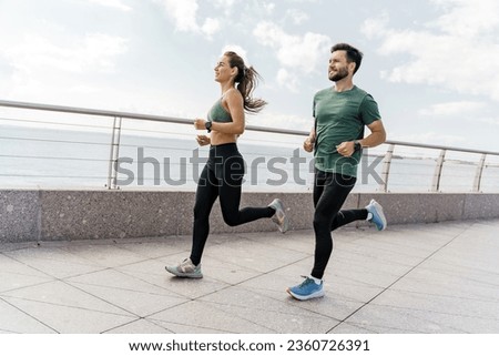 A group of friends exercises for cardio endurance, use a fitness watch and an app. Runners athletes in fitness clothes. Beautiful jogging in sports shoes. Motivation for a healthy lifestyle. Royalty-Free Stock Photo #2360726391