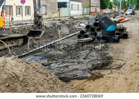 Street reconstruction view, old and new underground pipes next to a deep wide trench, pipe replacement