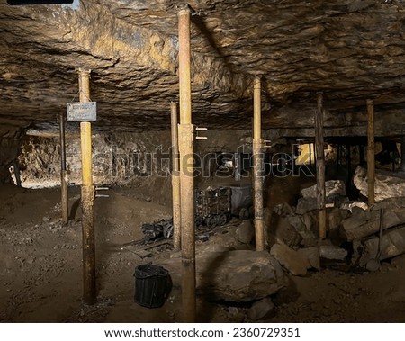 Underground of the historic silver mine in Tarnowskie Gory, a UNESCO heritage site. Wagons for the transport of excavated material and rock supports protecting against collapse. Royalty-Free Stock Photo #2360729351