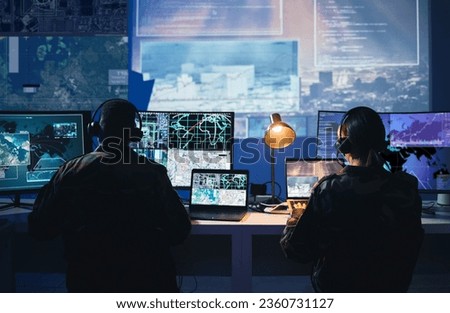 Military control room, computer screen and team with surveillance, headset and tech communication from back. Security, satellite map and man with woman at monitor in army office at command center. Royalty-Free Stock Photo #2360731127