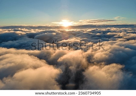 Aerial view from airplane window at high altitude of dense puffy cumulus clouds flying in evening Royalty-Free Stock Photo #2360734905