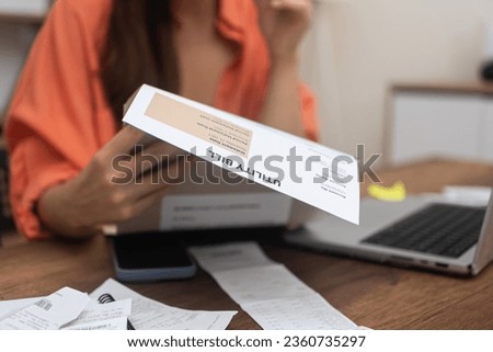 woman examines utility bills closely, wrestling with the escalating expenses of electricity, water, and internet services Royalty-Free Stock Photo #2360735297