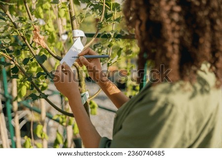 Close up of woman gardener signs the names of the plants in botanic center