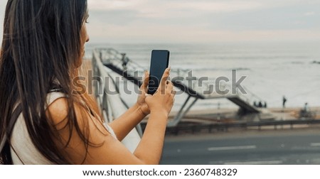 Young Latina woman taking a photo with her phone in front of the